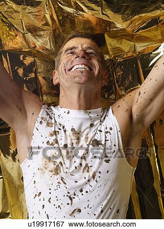 Stock Photo - Mud covered man with thermal blanket. Fotosearch