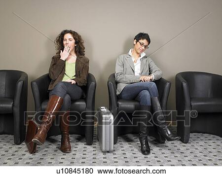 Stock Image - Two businesswomen sitting in waiting room. Brussels, Belgium.. Fotosearch