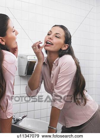 Woman reflected in office washroom mirror applying make-up View Large Photo Image Stock Photo - Woman reflected in office washroom mirror applying make-up. Fotosearch