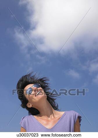 Stock Image - Woman smiling, blue sky. Fotosearch