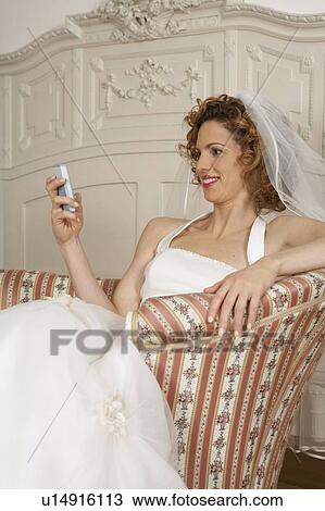 Stock Image - young bride smiling looking at mobile phone. Fotosearch