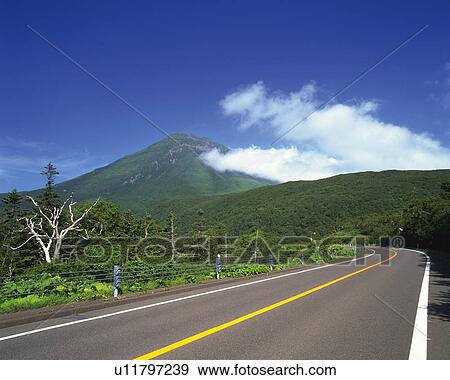 Stock Photo -  a Country Road, Heading to a Mountain Under a Blue Sky. Fotosearch