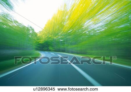 Stock Photography -  a Road, Surrounded By Several Trees, Front View, Blurred Motion, Aomori Prefecture, Japan. Fotosearch