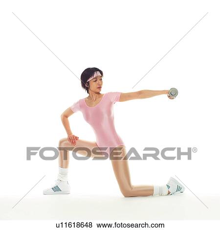 Stock Photo - A woman in Leotard exercising with a dumbbell, Side View, Copy Space. Fotosearch