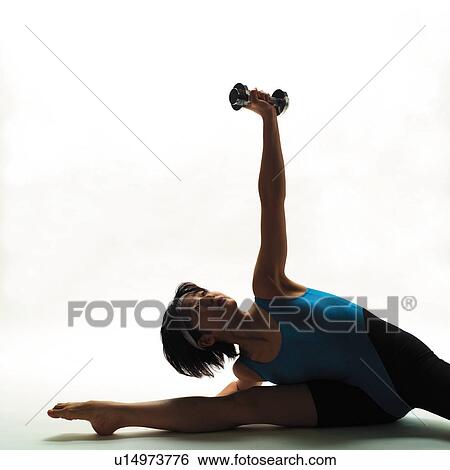 Stock Photograph - A woman in Leotard exercising with a dumbbell, Front View, Copy Space, Silhouette. Fotosearch
