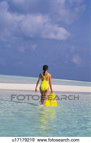 Stock Photo -  a Woman in a Yellow Badingsuit Walking Near the Beach, Rear View, Maldives, Micronesia. Fotosearch