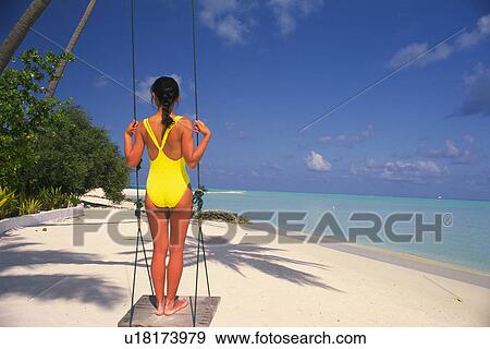 a Woman in a Yellow Bathing Suite Standing on a Swing, Looking at the Ocean With Its Clear Water, Rear View, Maldives, Micronesia View Large Photo Image Stock Photo - a Woman in a Yellow Bathing Suite Standing on a Swing, Looking at the Ocean With Its Clear Water, Rear View, Maldives, Micronesia. Fotosearch