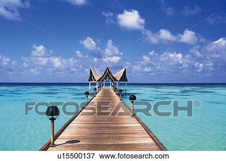 Stock Photo -  a Wooden Boardwalk, Heading to a Little wooden House, Surrounded By Ocean water, Front View, Maldives, Micronesia. Fotosearch