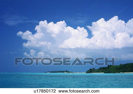 Stock Image -  The Republic of Maldives Under a Deep Blue Sky and Some Huge Clouds, Far View, Maldives, Micronesia. Fotosearch