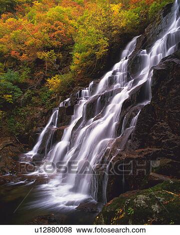 Stock Photo -  a Waterfall, Surrounded By Autumn-colored Leaves, Side View, Long Exposure. Fotosearch