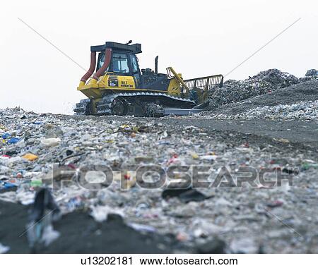 Bulldozer spreading trash in landfill, low angle view View Large Photo Image Stock Image - Bulldozer spreading trash in landfill, low angle view . Fotosearch