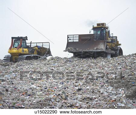 Bulldozers spreading trash in landfill, low angle view View Large Photo Image Stock Image - Bulldozers spreading trash in landfill, low angle view . Fotosearch