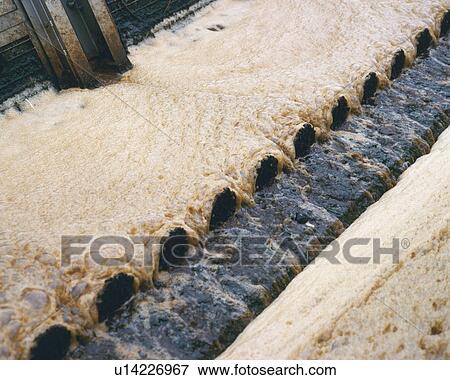 Stock Photo - Polluted water spilling from culvert, high angle view. Fotosearch