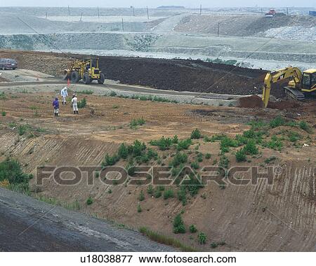 Stock Photo - Three men working at landfill, high angle view. Fotosearch