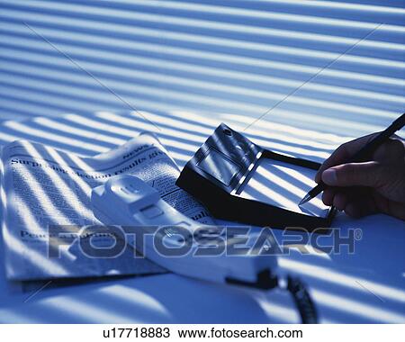 Stock Image - A hand making notes, High Angle View. Fotosearch