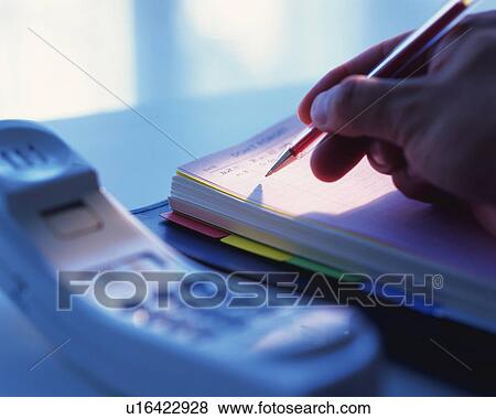 Stock Photo - A hand writing on a scheduler, Close Up, High Angle View, Differential Focus. Fotosearch