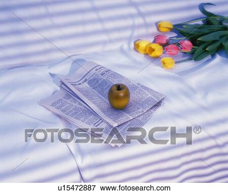 Stock Photo - Apple on newspaper and tulips, Close Up, High Angle View. Fotosearch