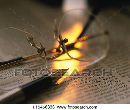 Stock Image - Glasses and pen on the newspaper, Close Up, High Angle View, Differential Focus. Fotosearch