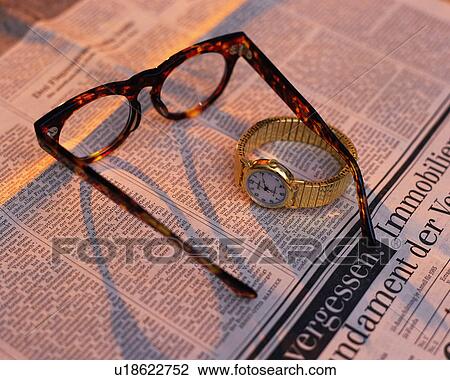 Stock Image - Glasses and watch on newspaper, Close Up, High Angle View. Fotosearch
