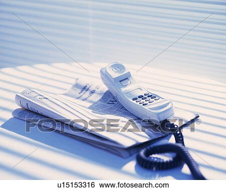 Stock Photograph - Telephone and newspaper on the table, Close Up, High Angle View. Fotosearch