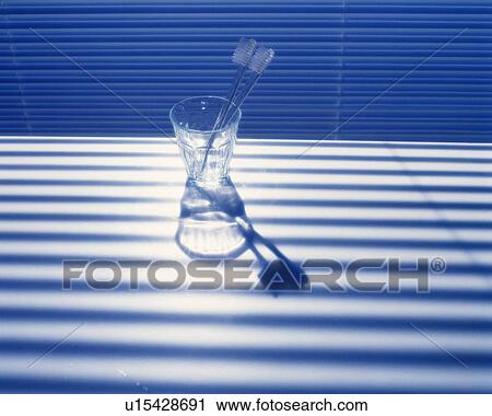 Stock Image - Two toothbrushes in the glass on the table, Close Up, High Angle View. Fotosearch