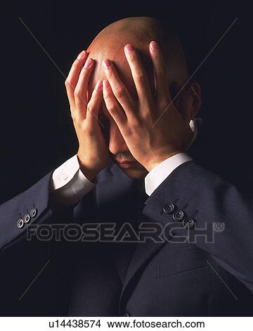 Picture - A bald headed businessman covering face with hands and thinking, Side View. Fotosearch