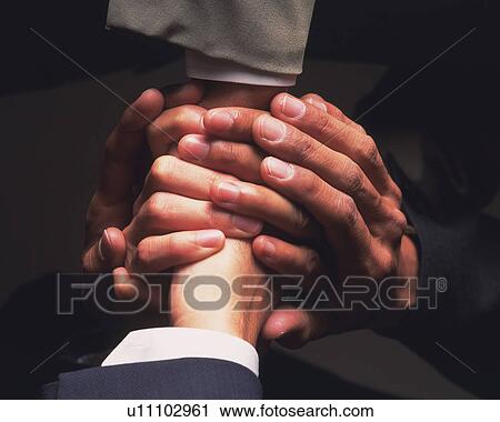 Stock Image - Three businessmen shaking hands, High Angle View, Close Up. Fotosearch