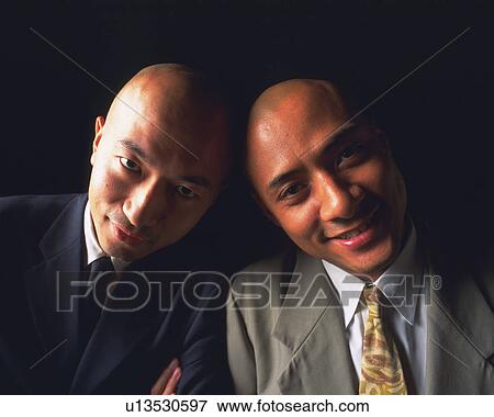 Stock Photo - Two bald headed businessmen smiling and posing at camera, Front View. Fotosearch