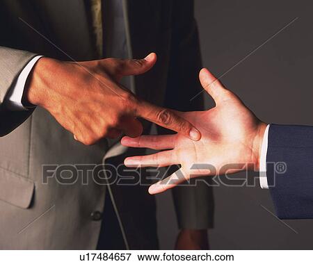 Stock Photo - Two businessmen playing paper-rock-scissors, Side View. Fotosearch