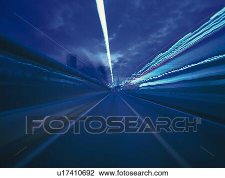 Stock Image -  a Highway By Night Under a Dark Blue Sky, Front View, Long Exposure, Blurred Motion. Fotosearch