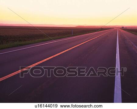 Stock Photo -  a Highway by Sunset, Surrounded By a Huge Flat Land. Fotosearch