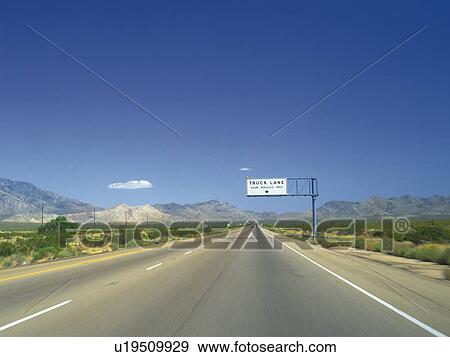 Stock Photo -  a Highway, Surrounded By Mountains Under a Blue Sky, Front View. Fotosearch