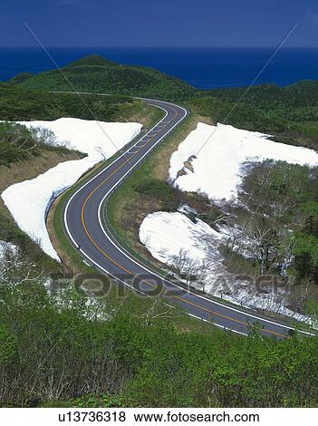 Stock Photo -  a Little Path Going Through Some Snow and Green Landscape, High Angle View. Fotosearch