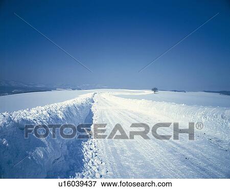 Stock Photo -  a Road Covered With Snow, Surrounded By a Snowy Landscape, Copy Space. Fotosearch
