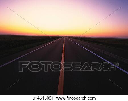 Stock Image -  an Asphalt Road By Sunset, the Horizon Reflecting the Colors of the Sun, Front View, Hokkaido Prefecture, Japan. Fotosearch