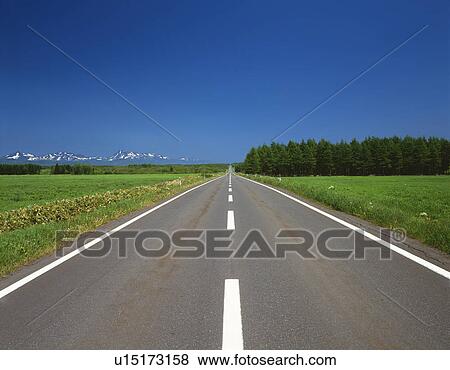 Stock Photo -  an Asphalt Road, Surrounded by a Flat Green Field Under a Blue Sky, Front View. Fotosearch