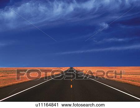 Stock Image -  an Asphalt Road, Surrounded By a Huge Flat Land Under a Blue Sky, Front View. Fotosearch