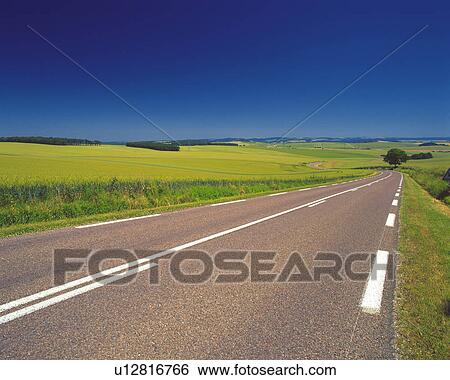 Stock Photograph -  an Asphalt Road, Surrounded By a Huge Flat Grassland Under a Blue Sky, High Angle View. Fotosearch
