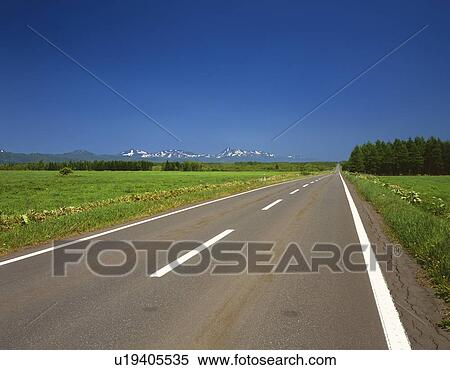Stock Photography -  an Asphalt Road, Surrounded By a Huge Field of Grass Under a Blue Sky. Fotosearch