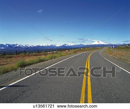 Stock Image -  an Asphalt Road Under a Deep Blue Sky and Some Snowy Mountains in the Background. Fotosearch