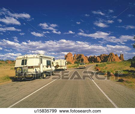 Stock Photo -  an Asphalt Road With Several Camping Cars Under a Blue Sky, Front View. Fotosearch