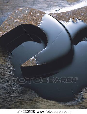 Stock Photo -  a Rusty Wench Covered With Oil, Lying on a Brown Surface, High Angle View. Fotosearch