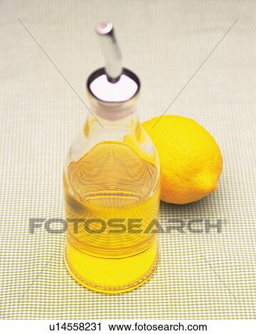 Stock Image -  a Small Flask With Some Yellow Oil Inside, Next to a Lemon, High Angle View, Differential Focus. Fotosearch