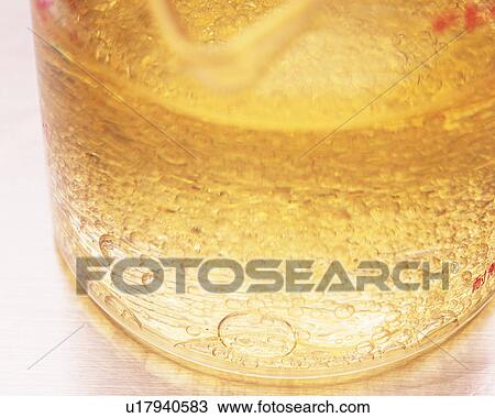 Stock Image - Beige-colored Oil in a Glass Beaker, Containing a Lot of Bubbler, High Angle View. Fotosearch