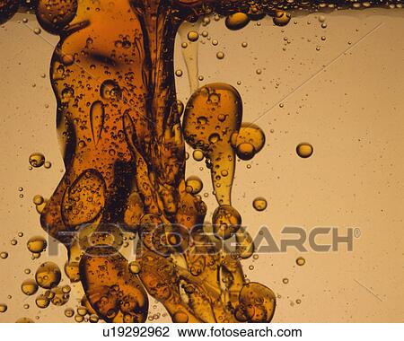 Stock Image - Brown-colored Oil Being Poured Into Another Liquid, Front View. Fotosearch