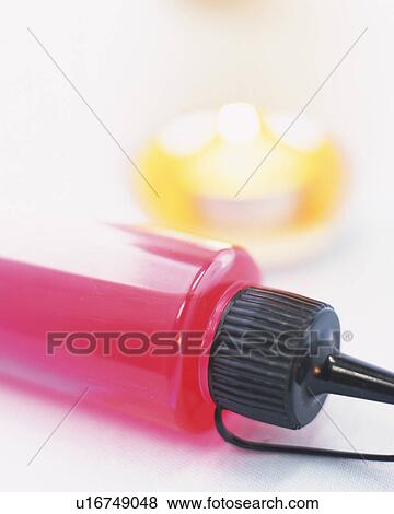 Stock Photo - Red-colored Aroma Oil in a Plastic Bin, Next to a Little Candle, High Angle View, Differntial Focus. Fotosearch