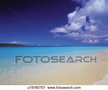Stock Photo -  a Beach With Clear Water Under a Blue Sky, Side View. Fotosearch