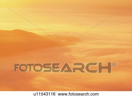 Stock Photograph -  a Sea of Clouds, Reflecting the Colors of the Setting Sun, High Angle View, Toned Image. Fotosearch