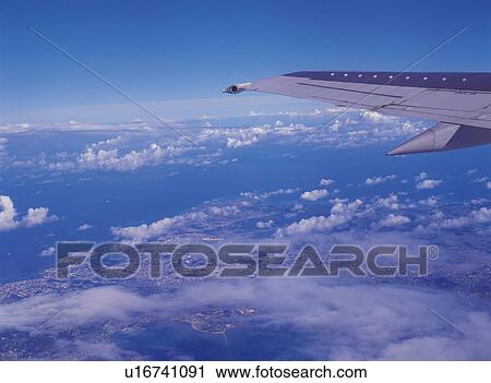 Stock Image -  a View From the Airplane, Several Clouds Under a Blue Sky, High Angle View. Fotosearch
