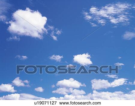 Stock Photo -  Several Small Clouds Floating in the Blue Sky, Low Angle View. Fotosearch